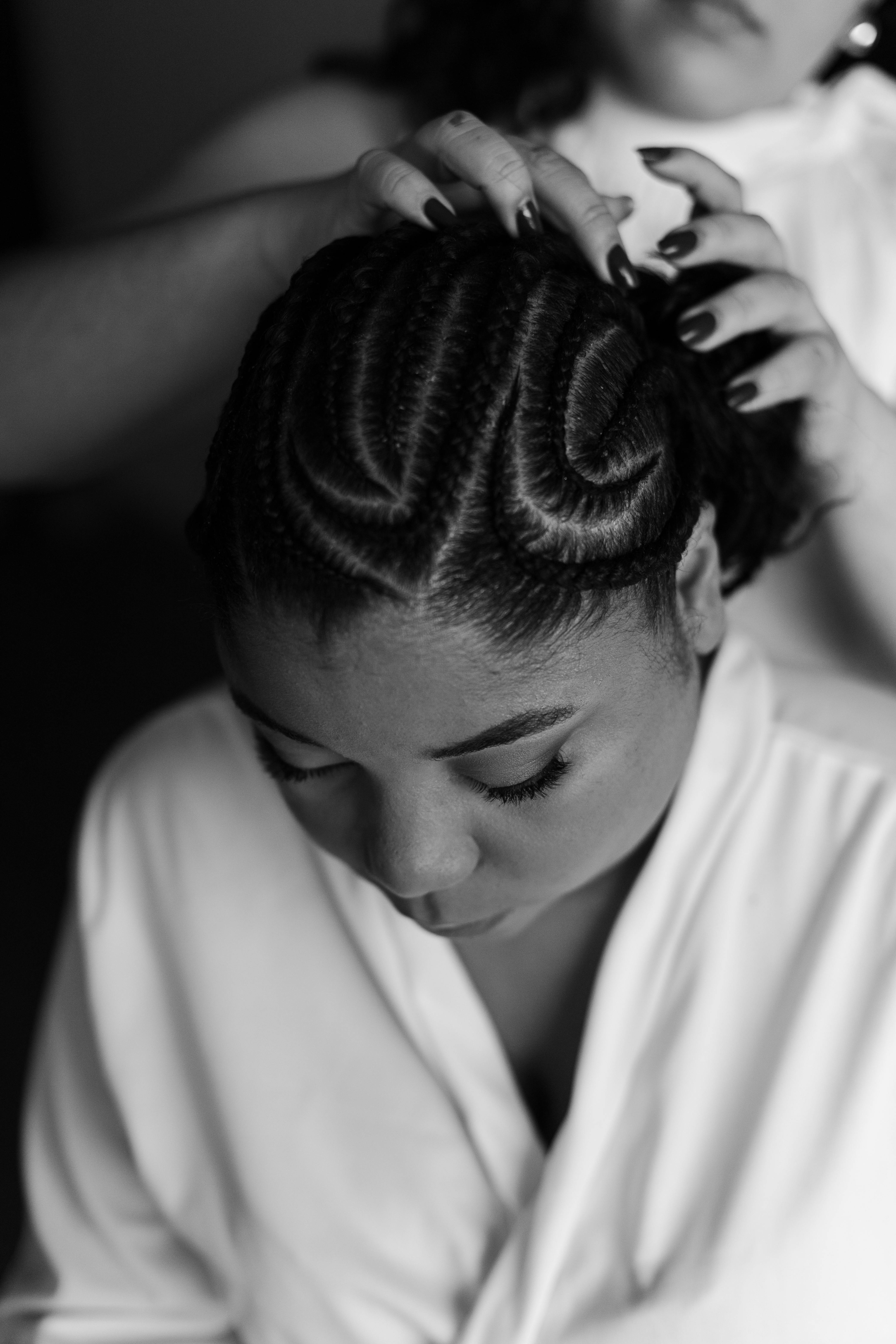 A stylist braiding a client's hair with careful, expert technique.
